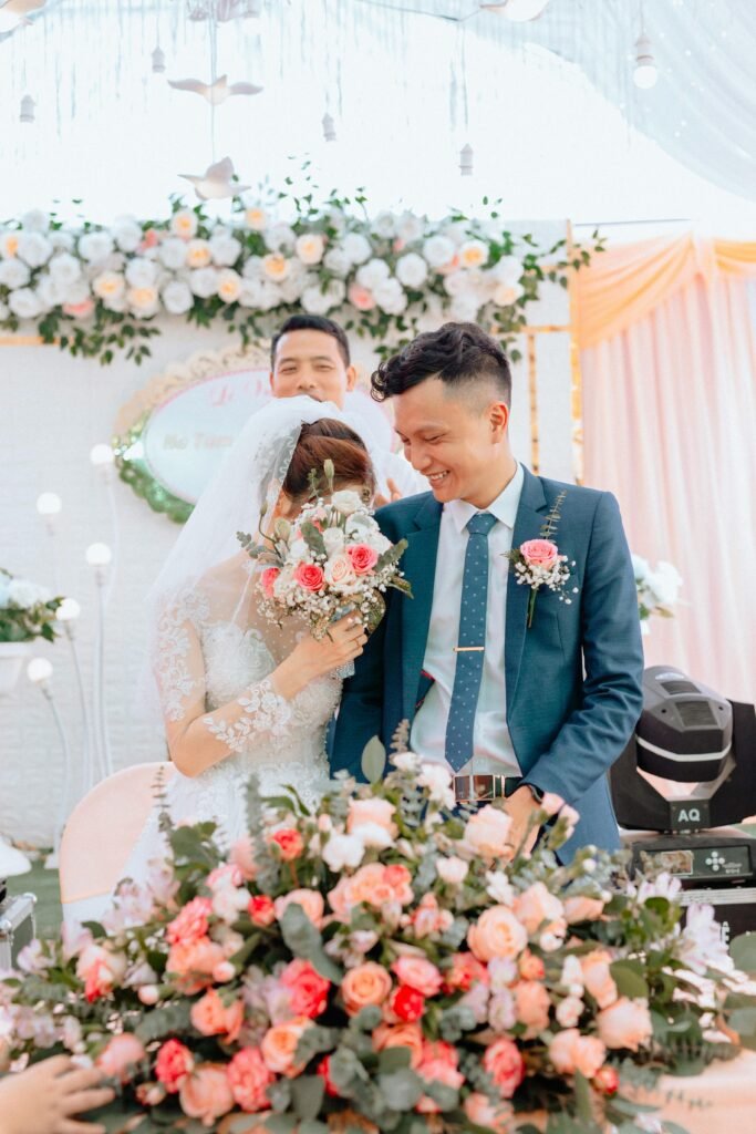 Newlyweds smiling amid lush floral arrangements during a bright wedding ceremony.